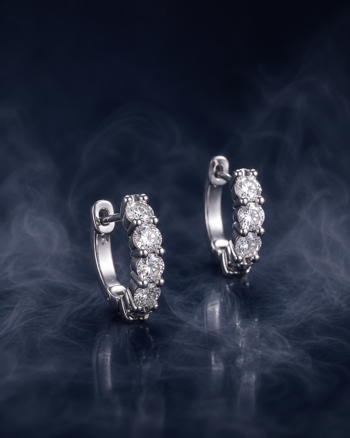 Ascot hoops, a pair of compact silver huggie hoop earrings set with a graduated line of round stones.